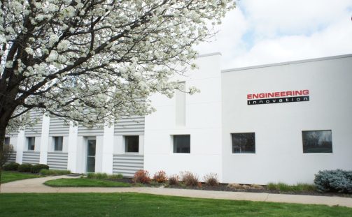 Outside view of Engineering Innovation's office building behind a tree with white flowers in bloom