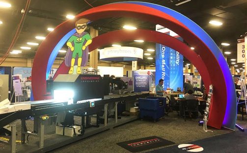 Engineering Innovation's trade show booth with a large red and blue arch set up above the Chameleon Parcel Sorting System at National Postal Forum 2016