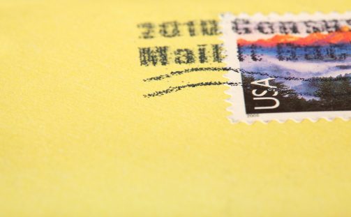 A close-up of a yellow envelope with a mailing stamp