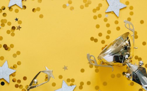 Trophy award with stars and confetti on a yellow background