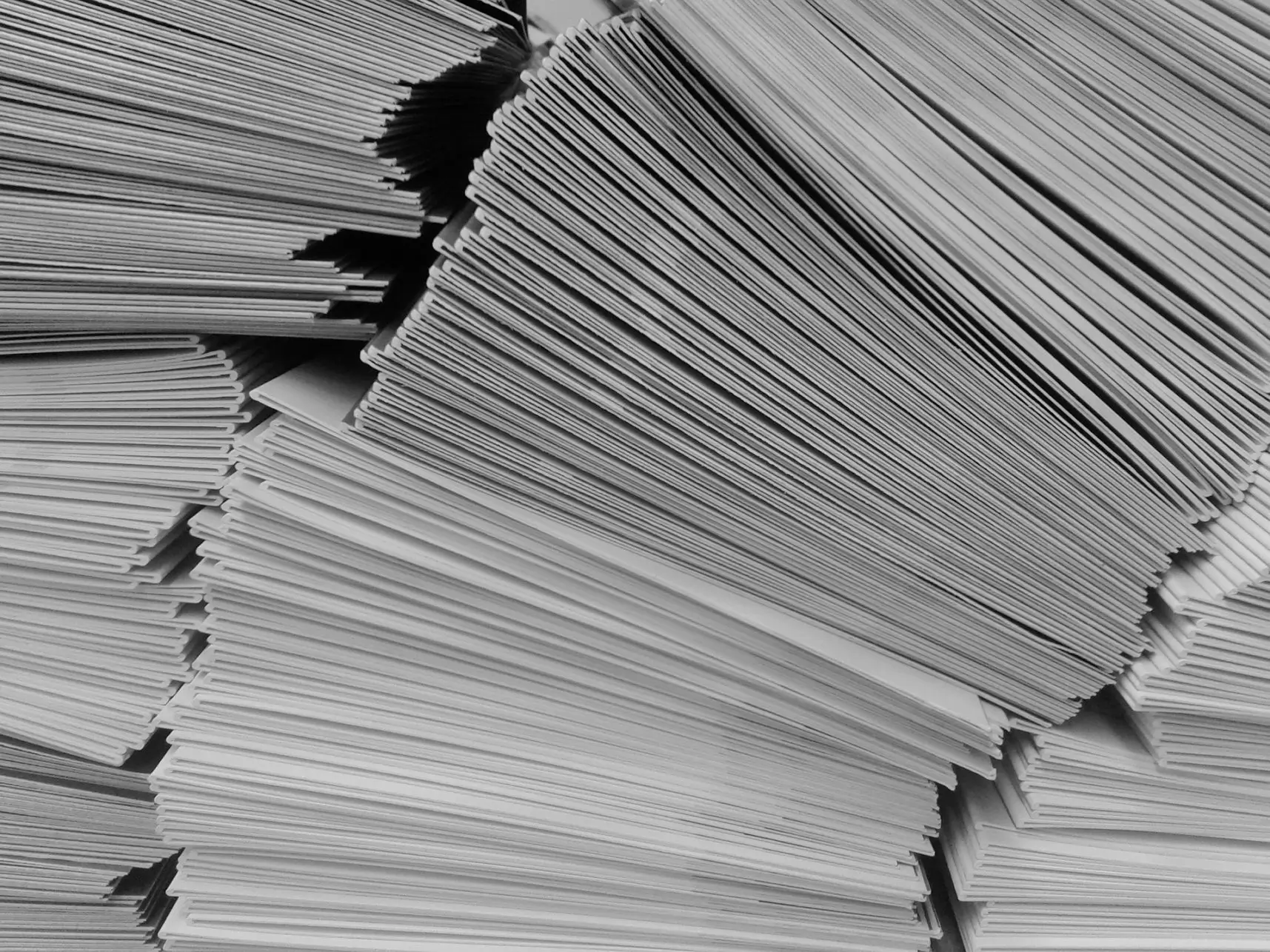 A black and white photo captures several tall stacks of paper sheets, neatly arranged. The papers create a pattern of lines and shadows, suggesting organized, voluminous documentation—perhaps alluding to the USPS August Rate Change preparation.