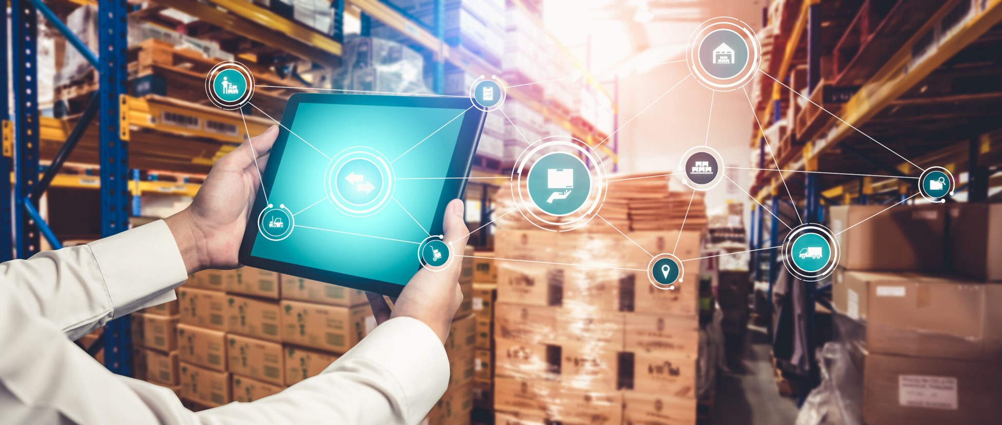 Person holding a tablet in a warehouse, featuring digital icons representing logistics and inventory management. Stacked pallets and shelves filled with boxes surround the scene, highlighting technology's role in modern supply chain operations.