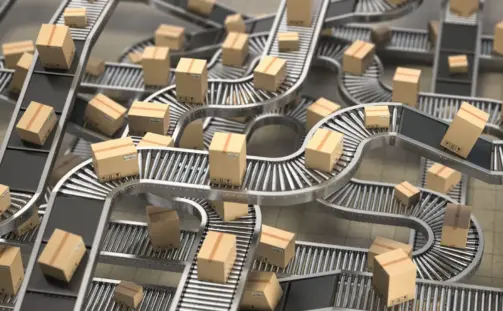 Numerous cardboard boxes on a complex network of conveyor belts, moving through a warehouse setting. The belts are interconnected in various loops and levels, creating an intricate distribution system.